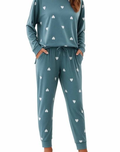 Woman in blue pajama set with white heart prints, sitting on a couch, front view with relaxed pose.