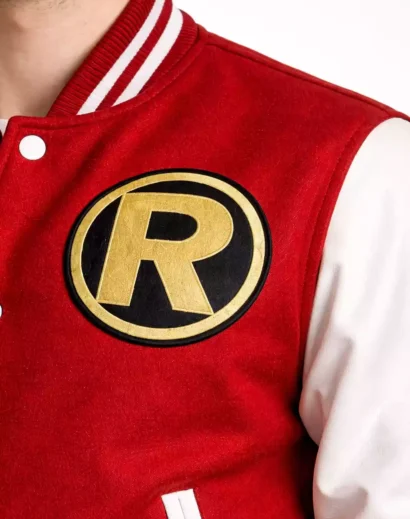 Close up of varsity jacket R logo patch and striped ribbed collar on red wool jacket