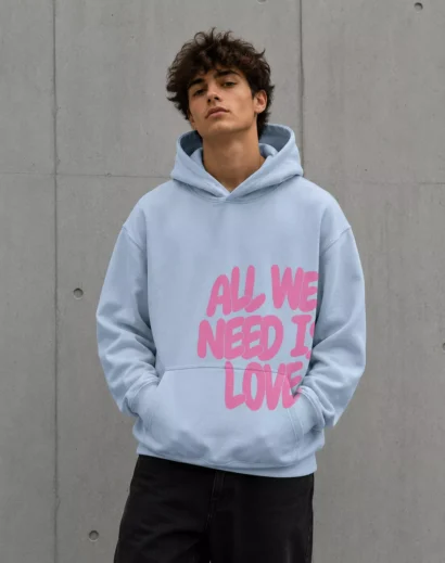 Young man wearing all we need is love hoodie blue oversized hoodie front side fashion portrait