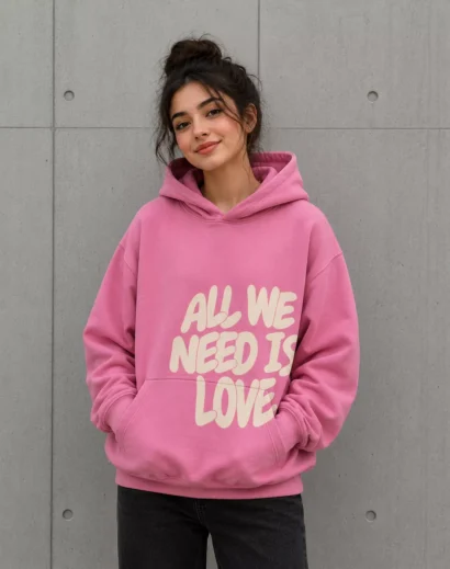 Female model wearing all we need is love hoodie original pink oversized hoodie front fashion style