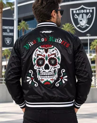 Man wearing a men's black letterman jacket with Viva Los Raiders lettering and detailed sugar skull embroidery